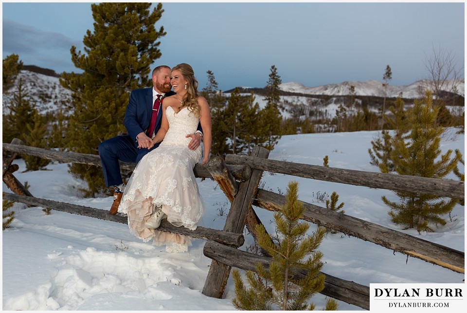 devils thumb ranch wedding in winter newlyweds sitting on fence