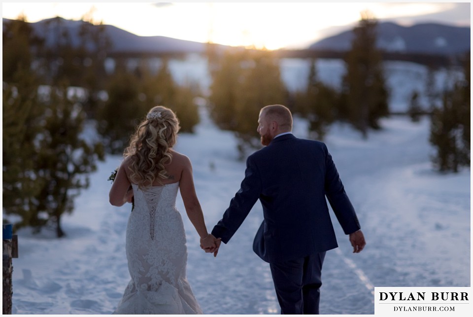 devils thumb ranch wedding in winter newlyweds walking into sunset