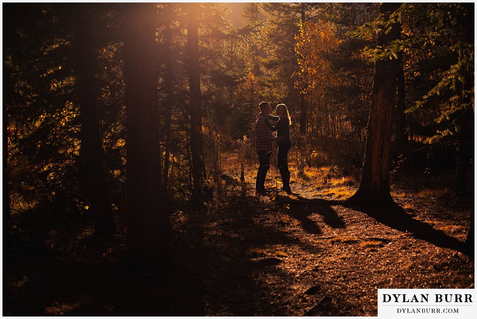 how to prepare for my engagement session couple standing in pine trees at sunset