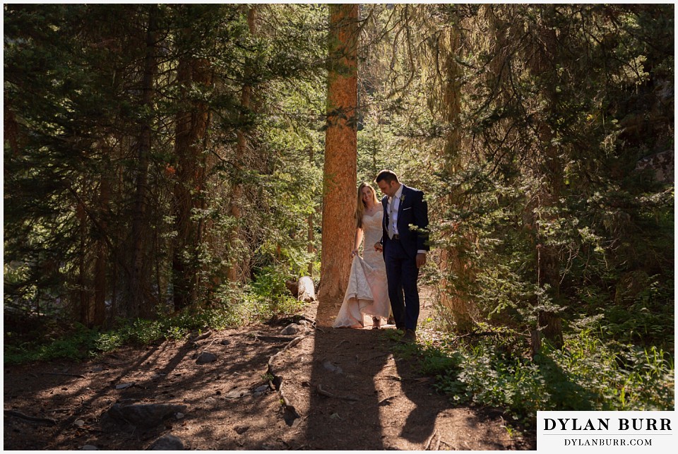 uncompahgre national forest colorado elopement wedding adventure bride and groom walking in the light between pine trees