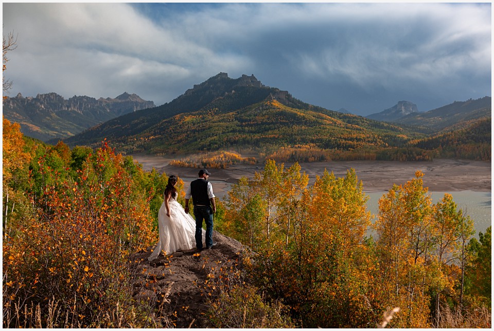 adventure elopement western colorado bride and groom walking out on rock with a huge fall colorado mountain view