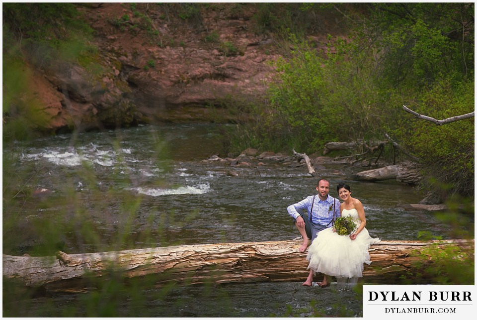 aspen wedding elopement bride and groom sittin on large tree across river