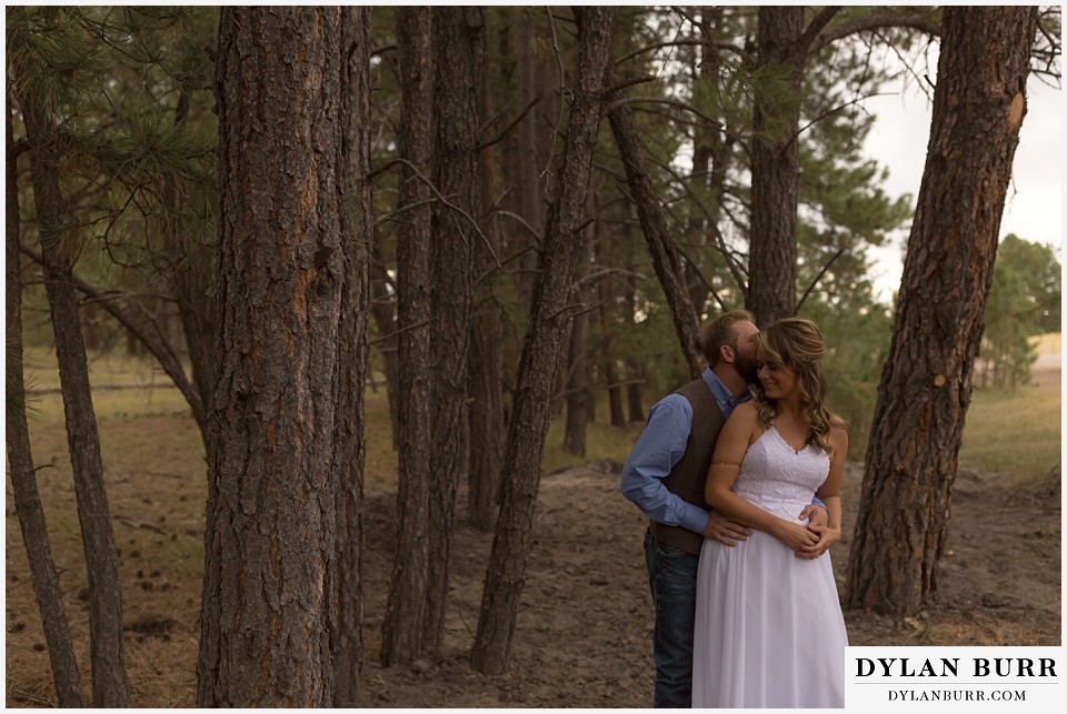 boho backyard colorado wedding groom kissing bride in the pine trees