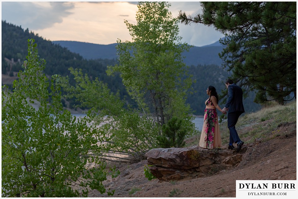 boulder colorado engagement session in the mountains couple standing on rock at sunset by the lake