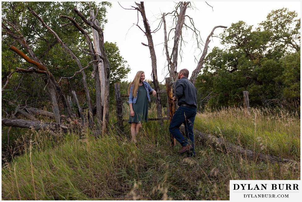 castlewood canyon engagement photos groom walking up to bride near a rough handmade fence