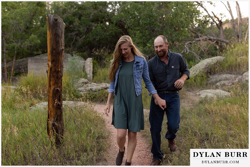 castlewood canyon engagement photos couple walking on trail and laughing