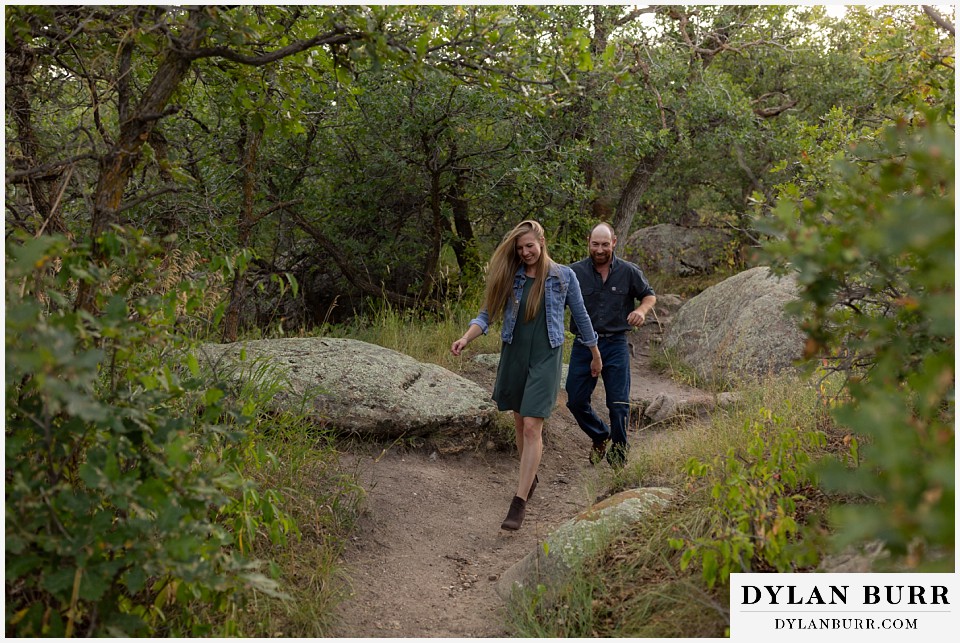 castlewood canyon engagement photos couple running down hiking trail