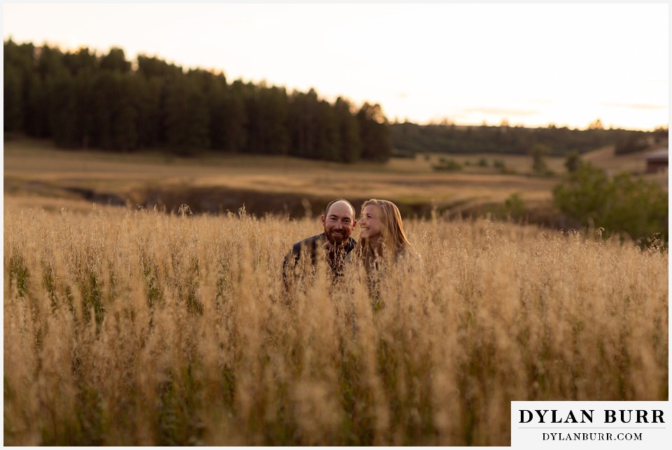 castlewood canyon engagement photos couple kneeling in tall grass being funny