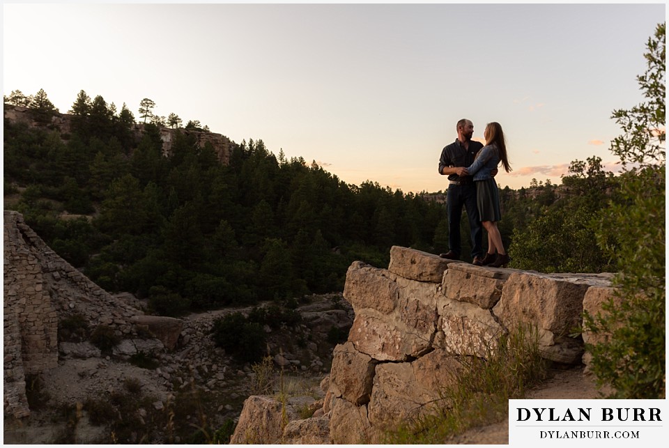 castlewood canyon engagement photos couple on walwl and he looks back at her