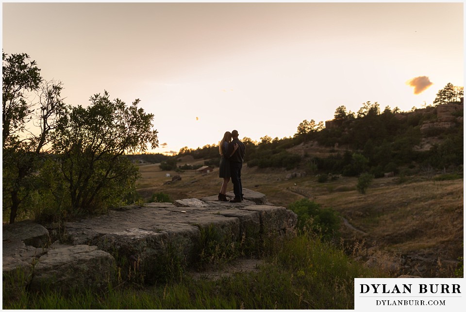 castlewood canyon engagement photos couple looking out at valley while enjoying the sunset
