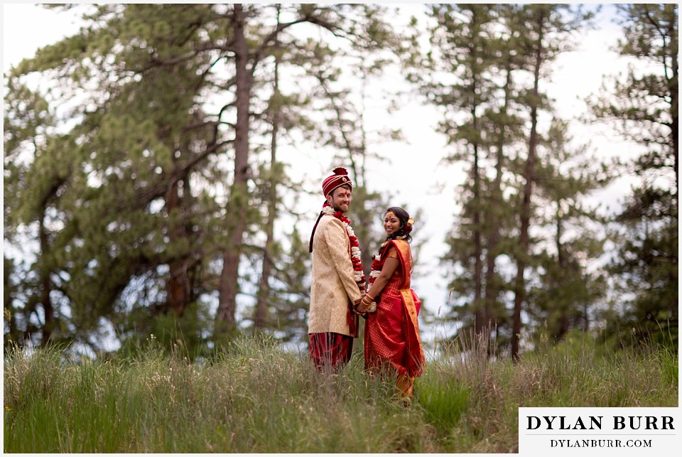 cielo at castle pines wedding colorado mountain wedding hindu bride and groom in field holding hands sari