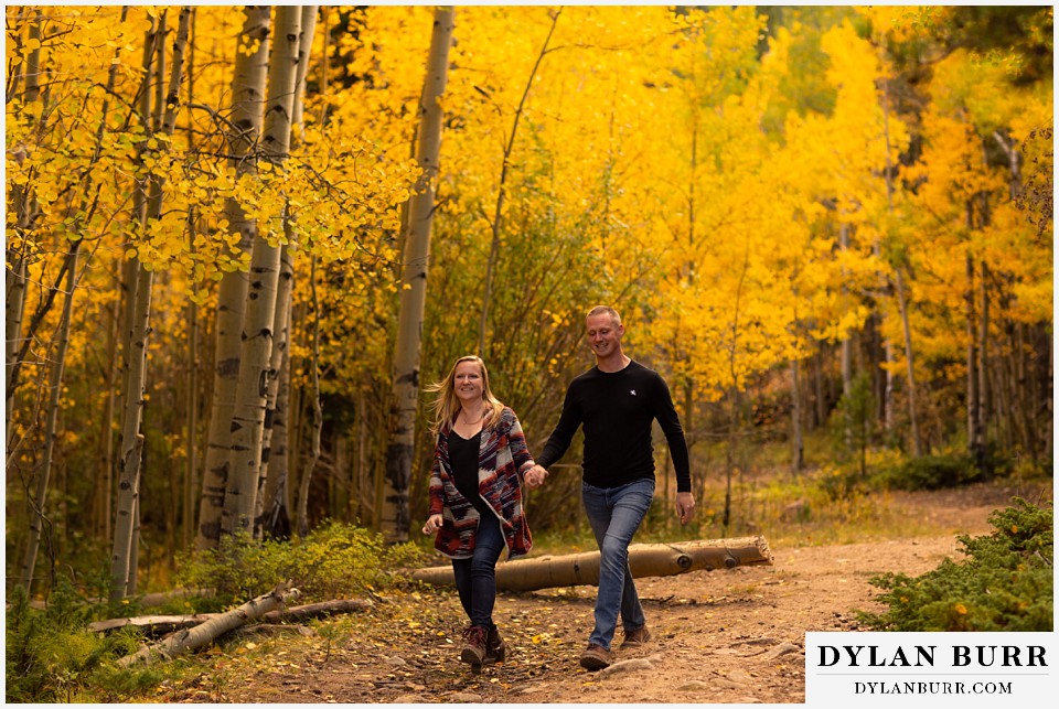 engagement photos in colorado couple skipping down mountain road
