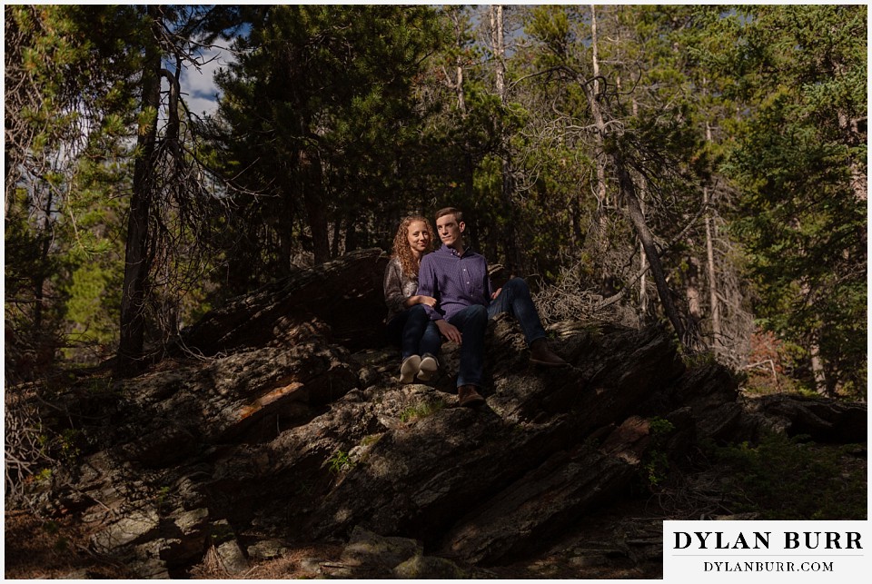 colorado mountain enagagement photo session couple sitting on rocks in a small pocket ot light