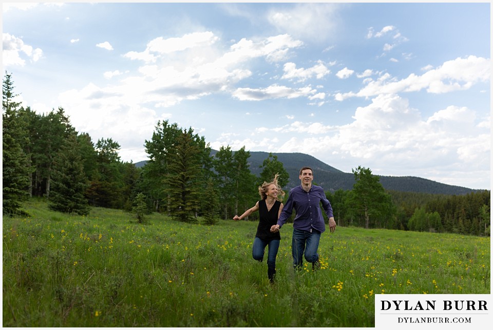 colorado mountain enagagement photo session running in meadow with wildflowers