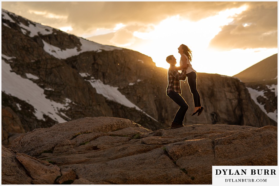 colorado mountain enagagement photo session lifting his fiance up in the air at sunset