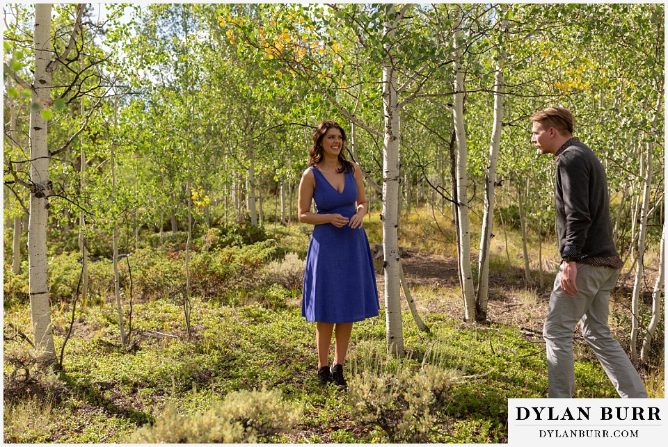 colorado mountain enagagement photos groom slowly approaching bride in bright blue dress