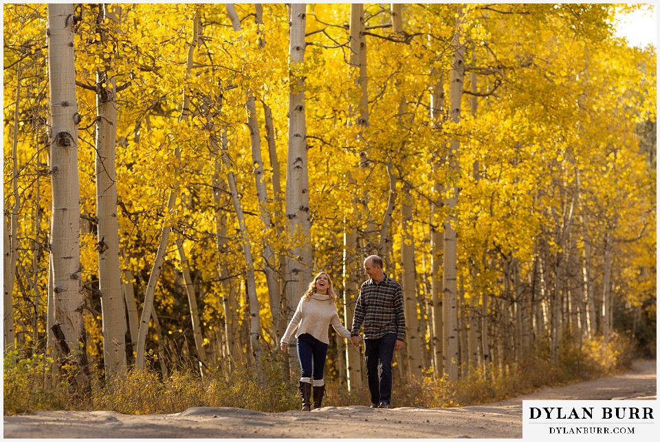 colorado engagement session in mountains couple walking on road in aspen trees