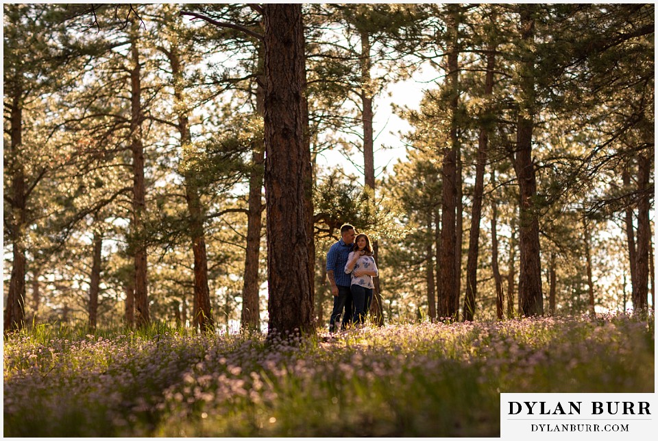 golden colorado mountain enagagement photo session couple hugging in pinewood forest