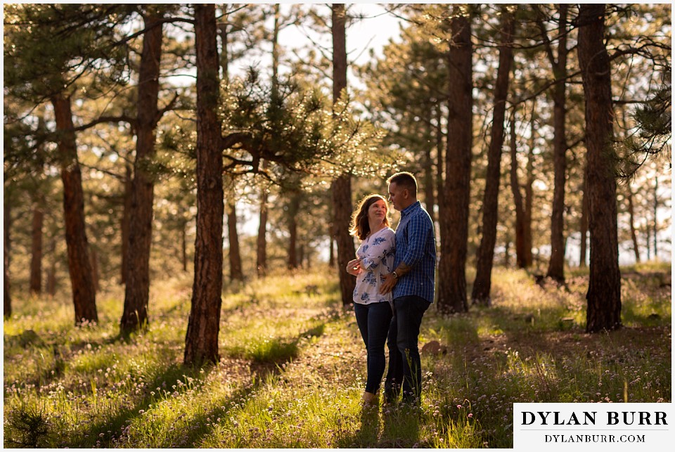 goldern colorado mountain enagagement photos couple standing in pine trees surrounded by sunlight