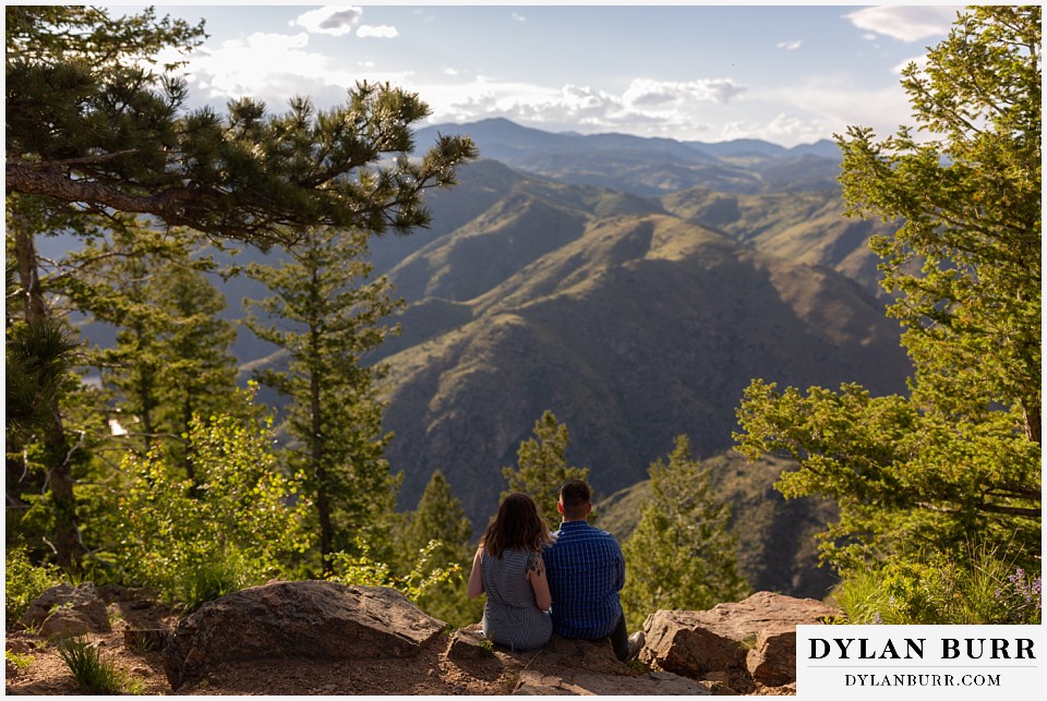 golden colorado mountain enagagement photo session couple sitting looking at large mountain valley