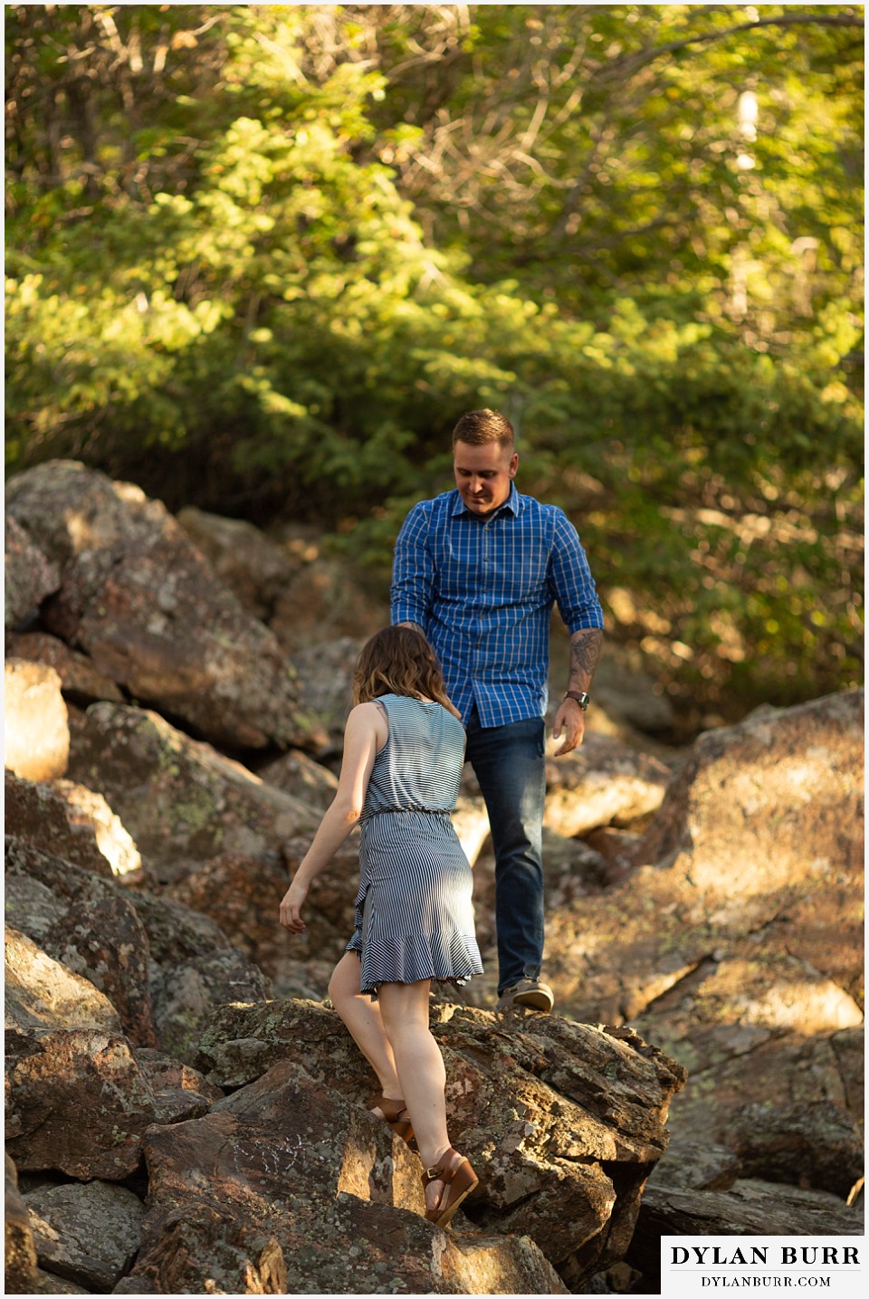 golden colorado mountain enagagement photo session couple hiking he helps her up on rocks