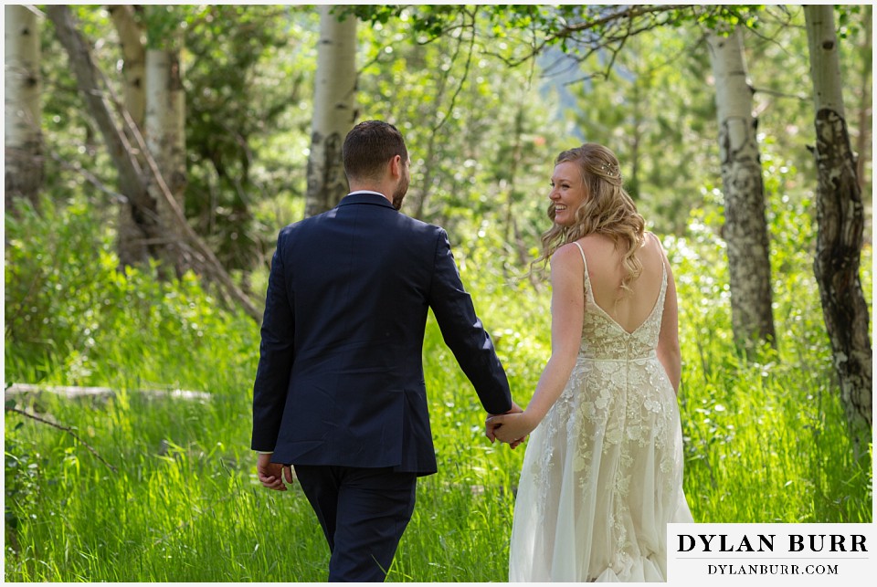 della terra mountain chateau wedding colorado rocky mountain national park wedding rmnp elopement bride and groom walking hand in hand in tall grass