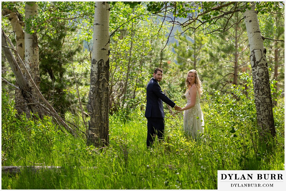 della terra mountain chateau wedding colorado rocky mountain national park wedding rmnp elopement bride and groom holding hands in aspen trees looking back