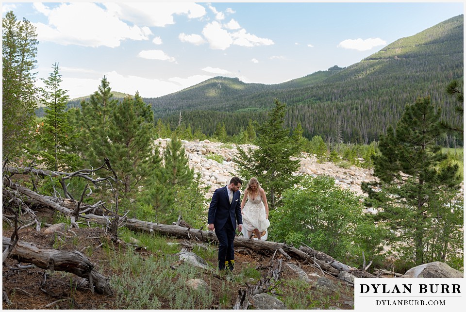 della terra mountain chateau wedding colorado rocky mountain national park wedding rmnp elopement bride and groom hiking over rocks and trees in forest