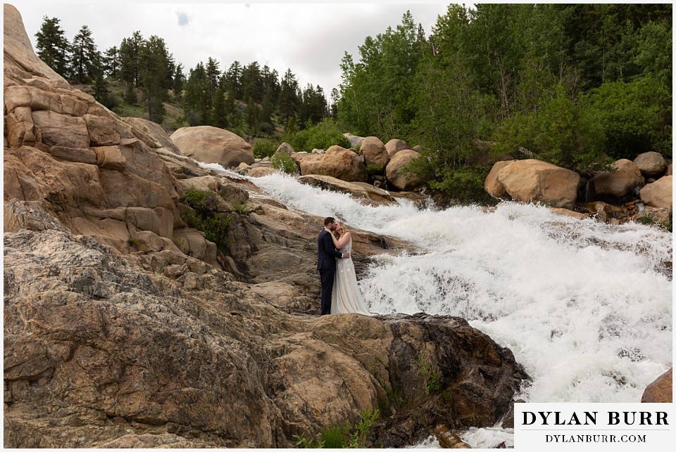 della terra mountain chateau wedding colorado rocky mountain national park wedding rmnp elopement bride and groom kissing next to massive waterfall