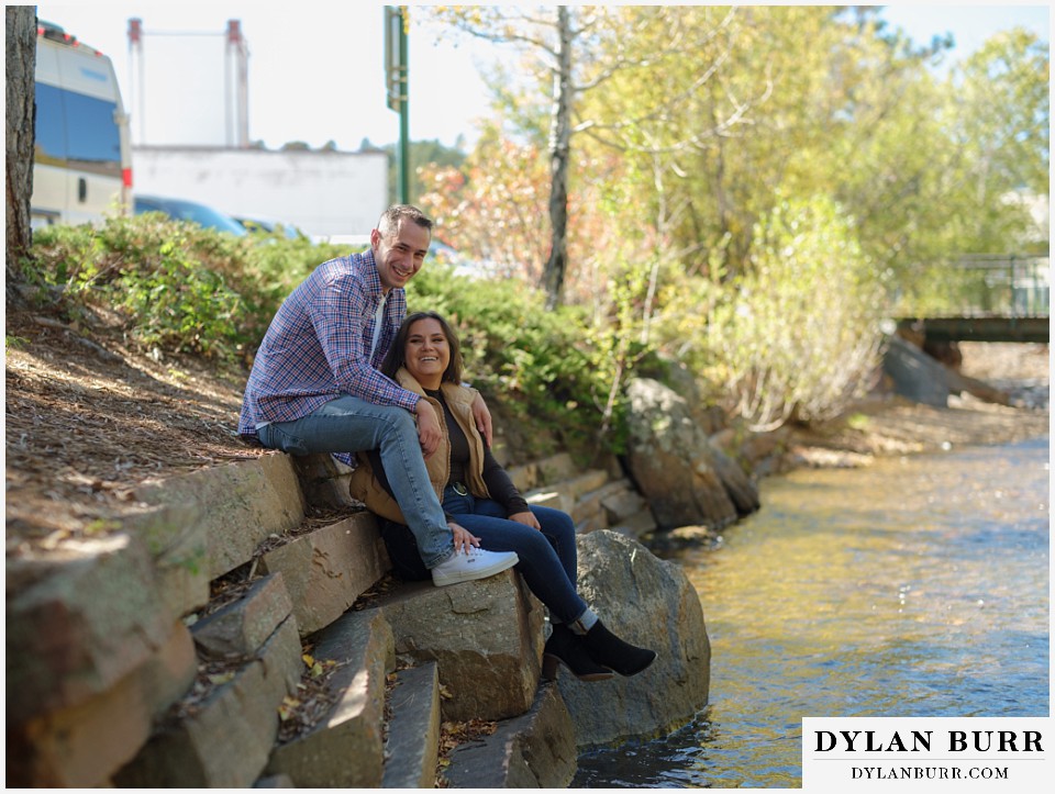 downtown estes park engagement photos sitting along the bank of the thompson river