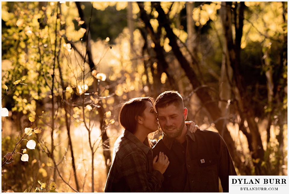 engagement photos golden colorado photographer couple whispering together in colorado mountains