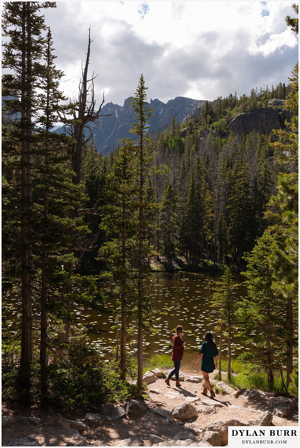 estes park engagement photos couple standing together near mountain lake