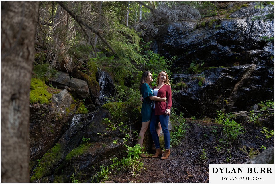 estes park engagement photos couple standing together near small waterfall and mossy rocks