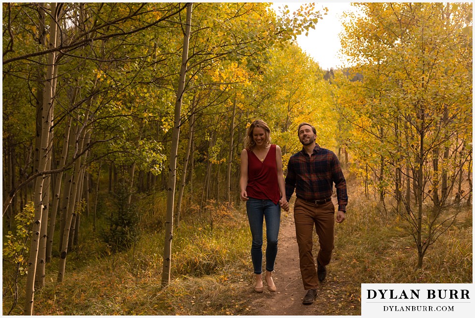 fall engagement photos in colorado couple holding hands in aspen tree trail