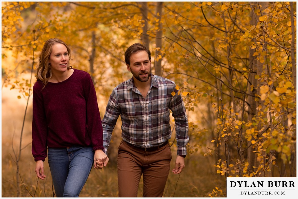 fall engagement photos in colorado couple walking together in golden forest