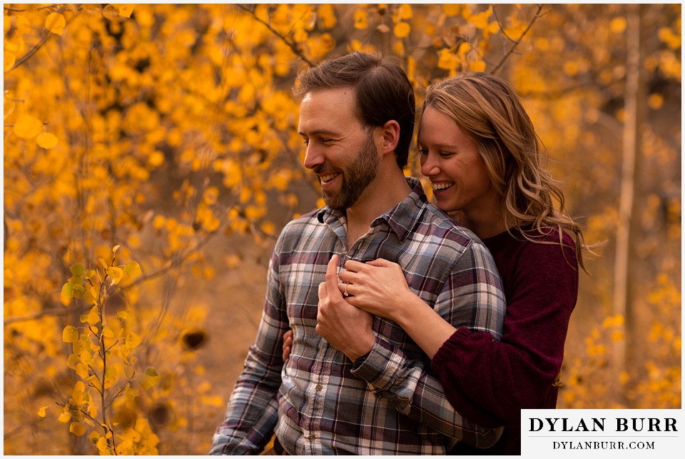 fall engagement photos in colorado couple laughing at joke from photographer