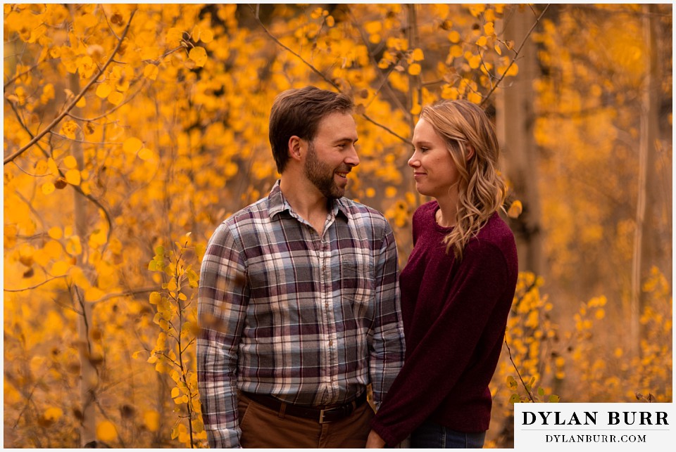 fall engagement photos in colorado couple in trees looking at each other with love
