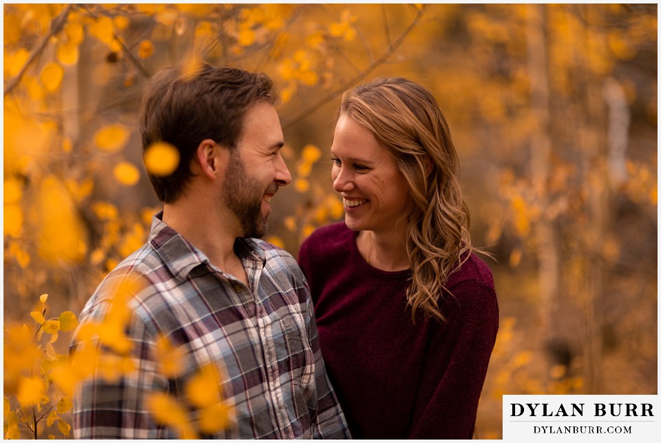 fall engagement photos in colorado couple lauging in yellow aspen leaves
