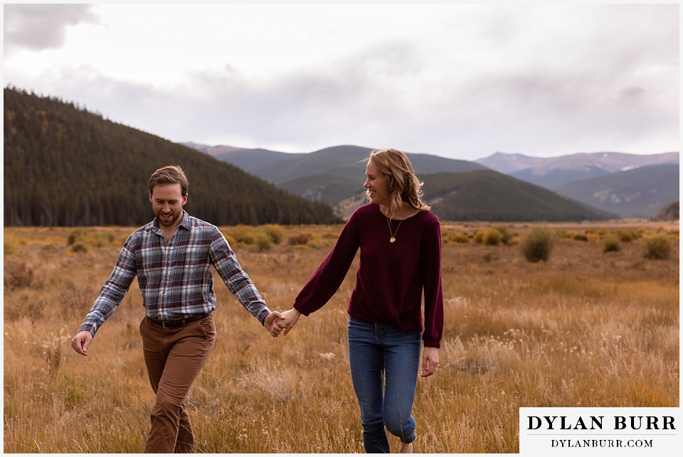 fall engagement photos in colorado couple walking together in mountain meadow