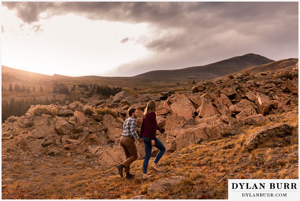 fall engagement photos in colorado couple walking up rocking hill