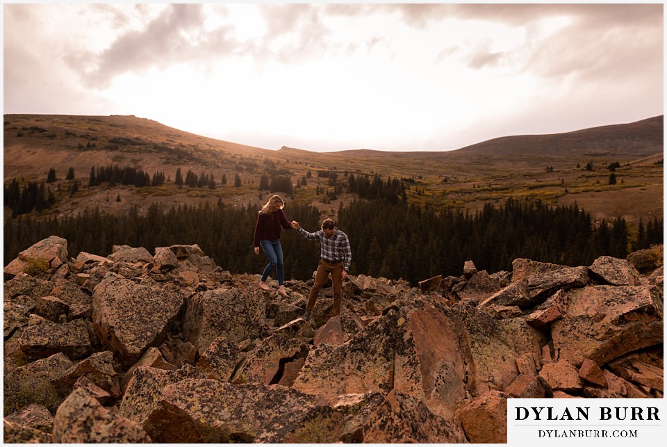 fall engagement photos in colorado couple walking down boulder pile in mountains