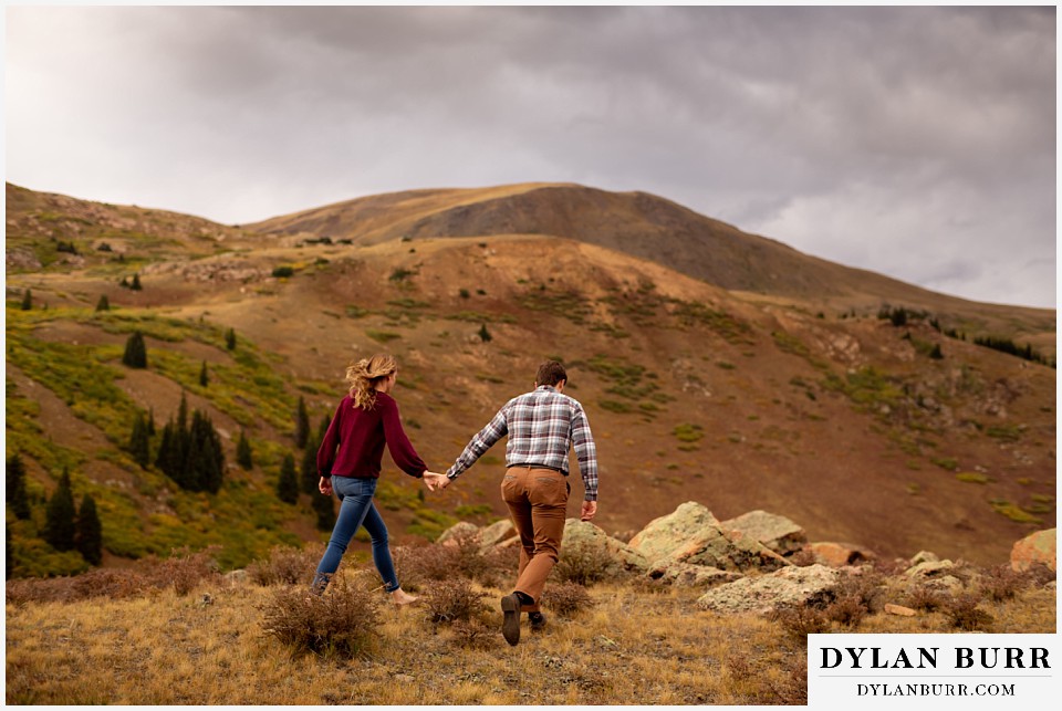 fall engagement photos in colorado couple walking on mountain top together