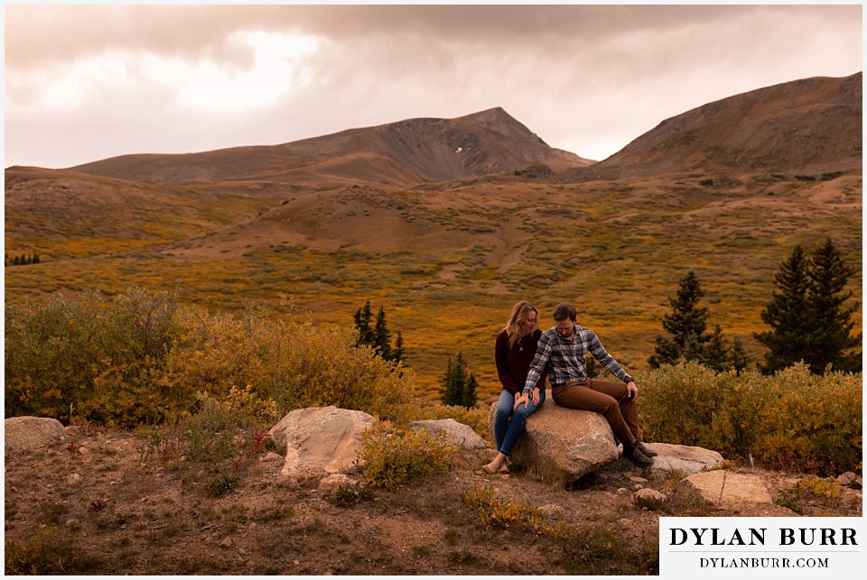 fall engagement photos in colorado couple sitting on rock together