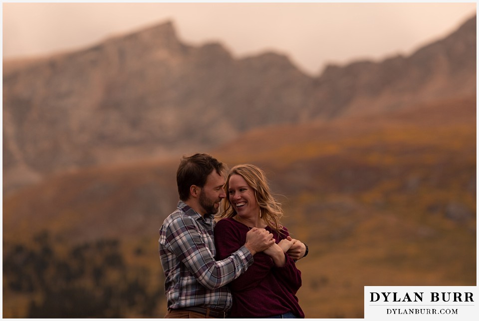 fall engagement photos in colorado pulling her in close in mountains 