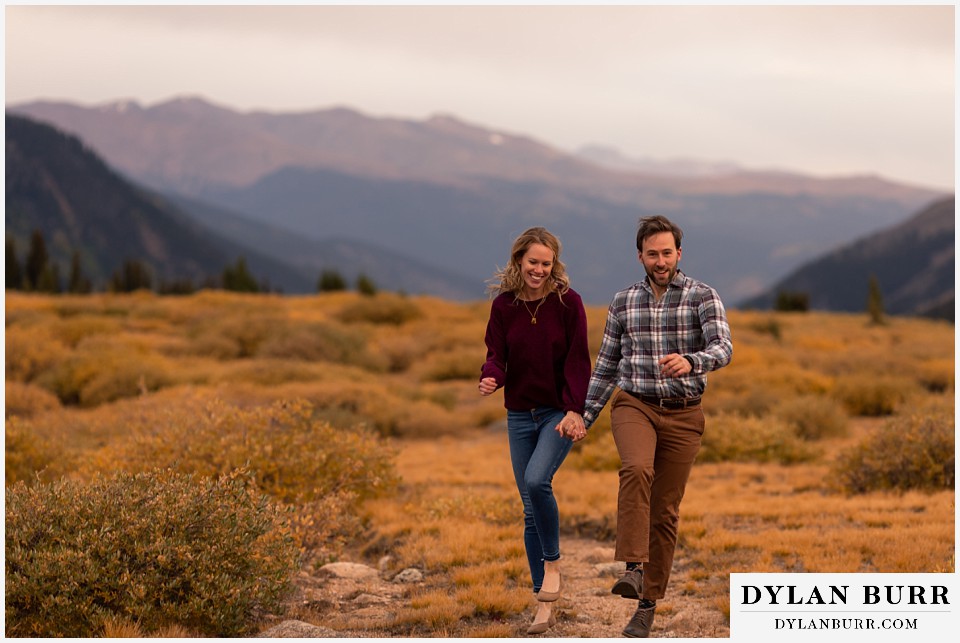 fall engagement photos in colorado couple jumping together in mountains