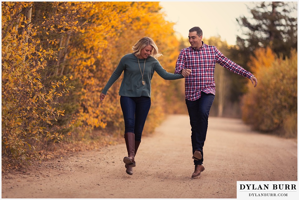 how to prepare for my engagement session couple skipping down road in fall colors