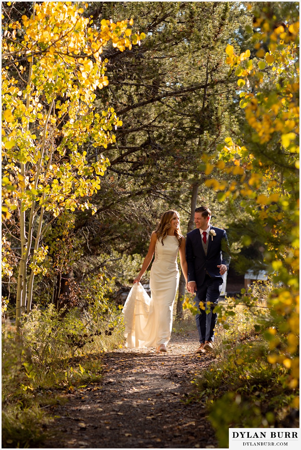jackson lake lodge wedding grand tetons wyoming bride and groom walking in yellow aspen trees