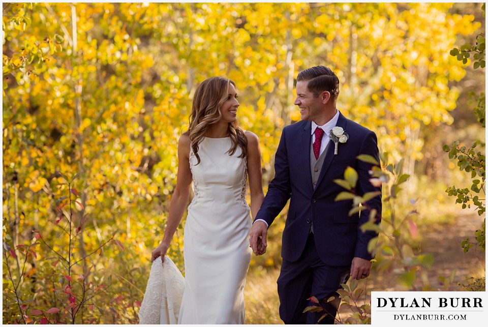 jackson lake lodge wedding grand tetons wyoming bride and groom walking in forest in the fall