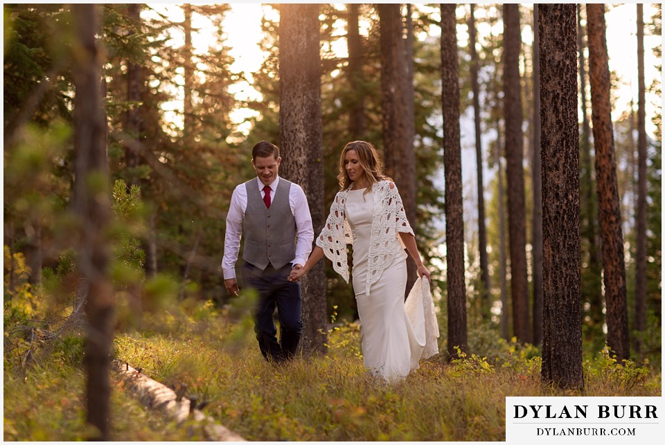jackson lake lodge wedding grand tetons wyoming bride and groom walking in pine tree forest