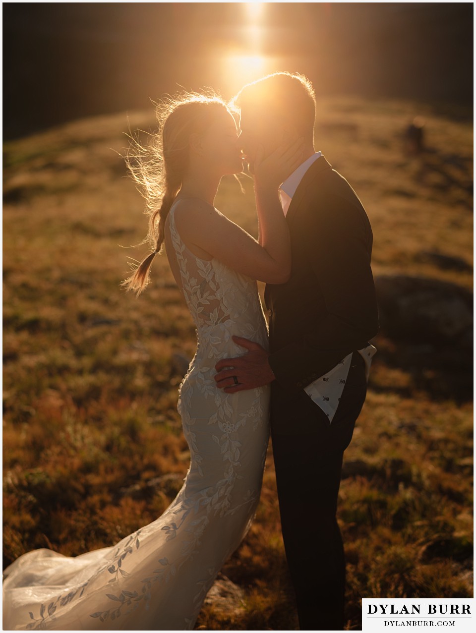 sunrise elopement wedding bride and groom kissing in the sunlight on top of a mountain